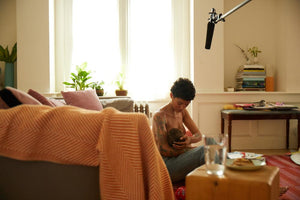 mother breastfeeding baby near bed ThirdLove