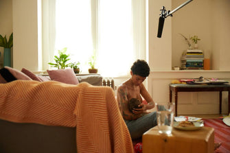 mother breastfeeding baby near bed ThirdLove