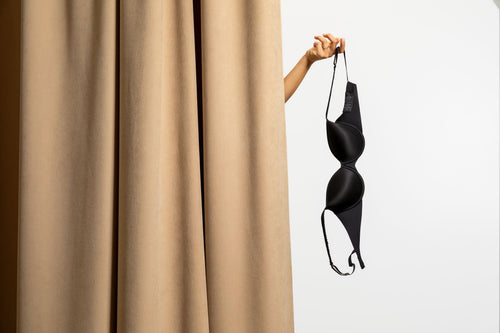 Woman checking her bra to see if her breasts will say. Wearing a bra may help prevent your breasts from sagging.