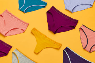 Different colored ThirdLove underwear lying flat on an orange background.
