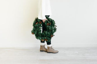 Woman holding holiday wreath in a minimal room